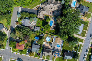 Birds eye view of suburban neighborhood showcasing houses with pools, gardens, landscaped yards at...
