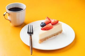 Cheesecake New York with cup of coffee on yellow background