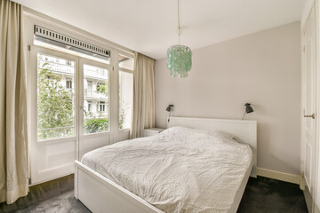 A serene bedroom featuring a comfortable bed, natural light streaming through large windows, and elegant decor, creating a peaceful ambiance for relaxation.