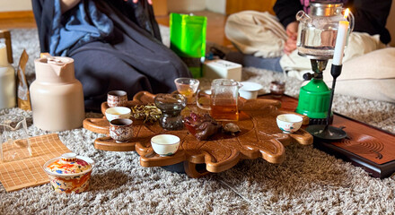 A woman pours yellow tea during a traditional gongfu tea ceremony on a carved wooden tray. Ritual, attention and mindfulness through tea preparation