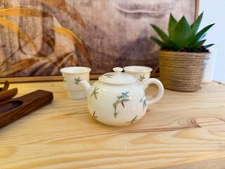 Small porcelain teapot with bamboo motif on wooden table. Harmony, tea culture, and peaceful atmosphere of traditional tea ceremony