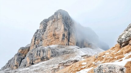 Fototapeta premium Magnificent mountain peak partially concealed by thick fog in winter time