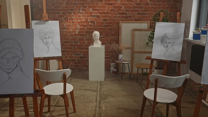 Shot of modern art class room, canvas with female pencil sketch portraits stand on easels and antique woman head model statue.
