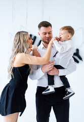 Family enjoying a playful moment indoors. A woman playfully feeds a young boy while a man watches in a bright indoor space.