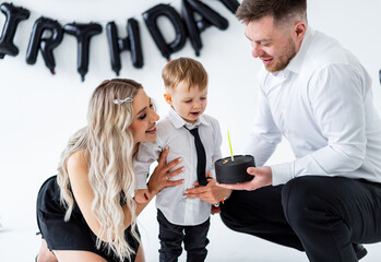 Celebrating a special birthday moment. A child excitedly receives a birthday cake from parents during a joyful celebration at home.