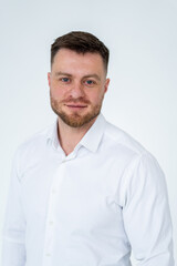Fototapeta premium Professional man in white shirt posing. A man stands confidently in a white button-down shirt against a plain background, looking directly at the camera.