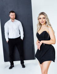 Couple in elegant outfits. A stylish couple poses in a studio, flaunting trendy outfits and confidence against a minimalist backdrop.