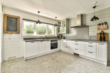 A contemporary kitchen featuring white cabinetry, stylish lighting, and an open layout with ample...
