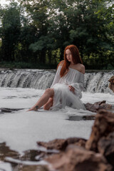 Aesthetic photo of attractive young woman in white translucent dress on river in image of nymph or mermaid