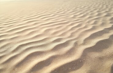 Obraz premium Close-up image of beige sand texture with wave pattern. Textured surface, sunny day, neutral tones. Natural background for design projects, website backgrounds. Ideal for vacation vibes.