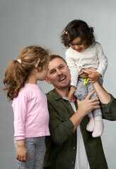 Laughing Father Holding Two Daughters. A happy father holds his two young daughters in his arms