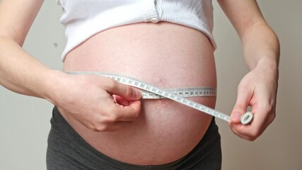 belly size during pregnancy, a woman measures her belly circumference in the ninth month of pregnancy - Powered by Adobe