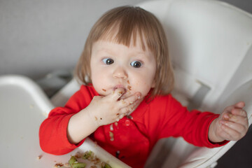Naklejka premium A small child eats buckwheat porridge on his own.