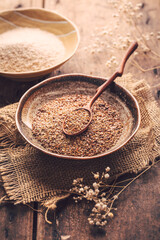 Shredded flax seeds and heap of psyllium husk (Isabgol) in a bowl on wooden table