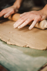 Hands skillfully shape a clay pot in a pottery studio. The workshop encourages creativity and focuses on teaching pottery techniques to beginners in a relaxed atmosphere.