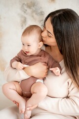 mom and baby, maternal love and care, a mother holds a baby in her arms, gently kissing and hugging him at home, a mother with a small child on maternity leave