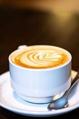 A cup of cappuccino on a saucer with a spoon