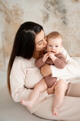 mom and baby, maternal love and care, a mother holds a baby in her arms, gently kissing and hugging him at home, a mother with a small child on maternity leave