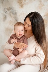 mom and baby, maternal love and care, a mother holds a baby in her arms, gently kissing and hugging him at home, a mother with a small child on maternity leave