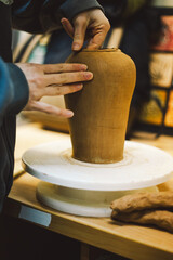 Hands skillfully shape a clay pot in a pottery studio. The workshop encourages creativity and focuses on teaching pottery techniques to beginners in a relaxed atmosphere.