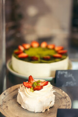 Desserts on display, Pavlova embellished with fresh fruit, strawberries.