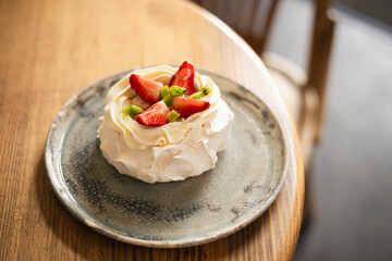 Pavlova cake with whipped mascarpone cream and fresh strawberry slices in cafe.