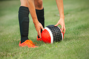 Child football player in red boots and black football socks with a red ball playing football. Passing the ball in football.