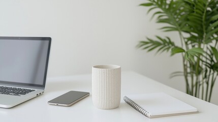 Minimalist workspace with laptop, phone, cup, and notebook