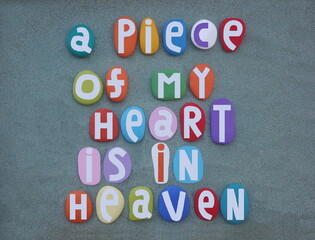 A piece of my heart is in heaven, creative nostalgic phrase composed with multi colored hand painted stone letters over green sand