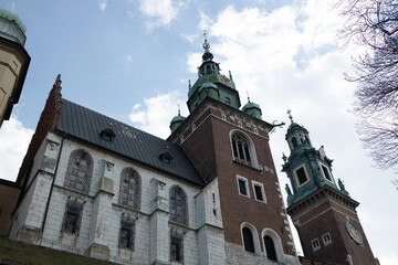 Fototapeta premium Historic cathedral building in Krakow, Poland, featuring tall towers and intricate architecture. The photo is taken against a clear blue sky, highlighting the grandeur and beauty of the church