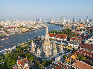 Fototapeta premium Aerial view pagoda buddha Temple of dawn Wat Arun river background sunset light with modern downtown city background