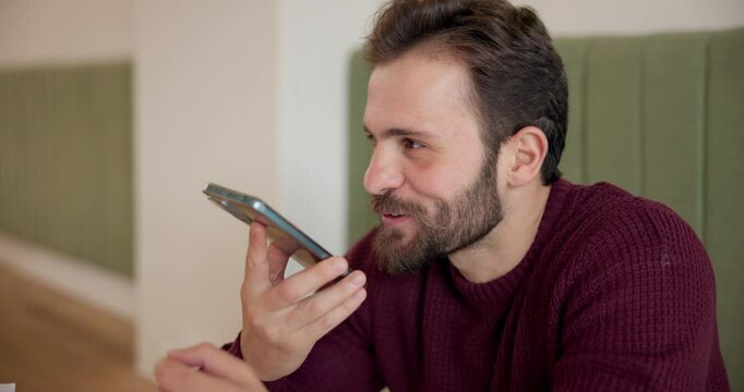 Happy man, conversation or phone call with speaker at cafe for voice note or vocal recording. Male person, freelancer or communication with smile on mobile smartphone for audio message at coffee shop