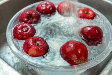 Washing red apples float in the water at home kitchen.