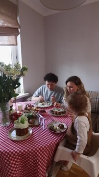 A family gathers around a checkered tablecloth to share a delicious homemade meal. Happy family celebrating Easter at the dinner table.