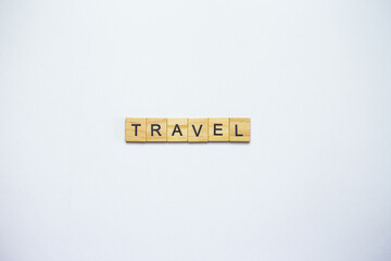 Wooden letter tiles spelling out the word TRAVEL on a white background