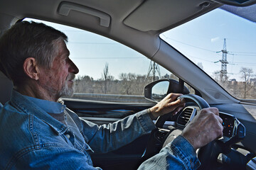 An elderly man drives an electric car.