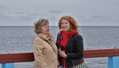 A mother and her adult daughter against the backdrop of the sea.