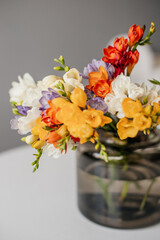 Bouquet of multi-colored freesias in a green glass vase. Spring bouquet of white, yellow, orange...