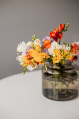 Bouquet of multi-colored freesias in a green glass vase. Spring bouquet of white, yellow, orange...