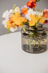 Bouquet of multi-colored freesias in a green glass vase. Spring bouquet of white, yellow, orange and purple freesia. Bridal bouquet. Bright spring flowers