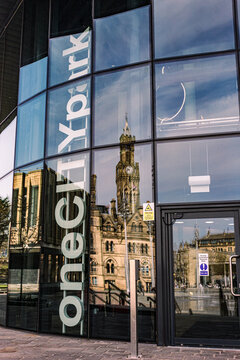 Bradford's Victorian City Hall with its famous clock tower is reflected in the entrance of One City Park the  latest iconic building as the city regenerates