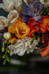 Bouquet of multi-colored freesias in a green glass vase. Spring bouquet of white, yellow, orange...