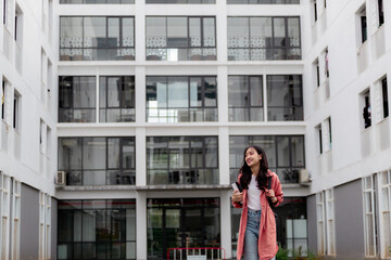 Smiling student walking in university campus holding books and backpack