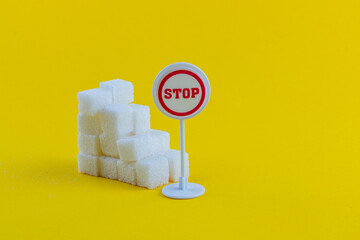 Stop sign next to sugar cubes on bright yellow background