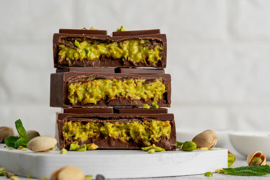 Dubai chocolate with kadayif dough and pistachio paste. Trend dessert on a board on a concrete background. Copy space.