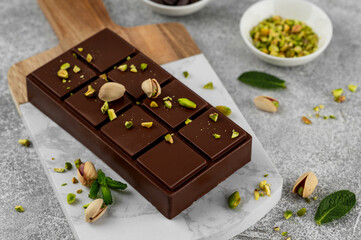 Dubai chocolate with kadayif dough and pistachio paste. Trend dessert on a board on a concrete background. Copy space.