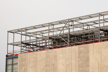 Naklejka premium concrete building and metal beam frame during construction against grey sky