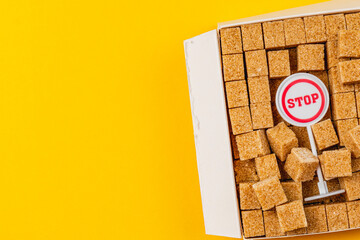 Brown sugar cubes fill a white box, topped with a small sign that reads stop
