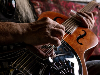 Male musician hand play Vintage Resonator acoustic dobro blues slide guitar.