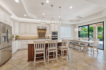 A kitchen with white cabinets, stainless appliances, and a large island